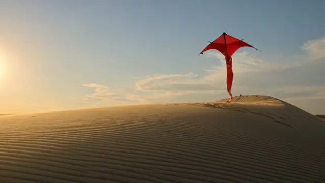 Kling V3 Pro result for the prompt a red kite rising over a windswept dune at golden hour, camera tilting up: a red kite above the crest of a dune